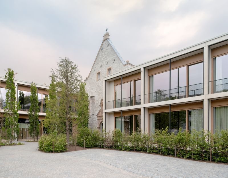 Luftaufnahme eines modernen Gebäudekomplexes, umgeben von Bäumen – Standort der TAP Holding. Das Headquarter der TAP Holding sind die Jacoby Studios und wurden nach Entwürfen von David Chipperfield Architects Berlin gebaut.