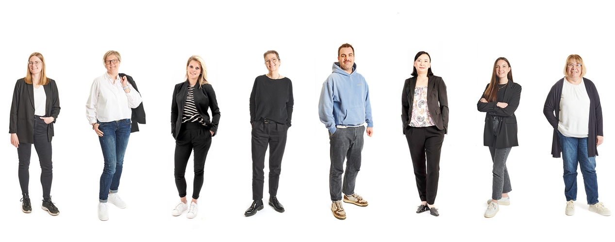 Mitarbeitende der TAP Holding Unternehmensgruppe stehen nebeneinander vor weißem Hintergrund 